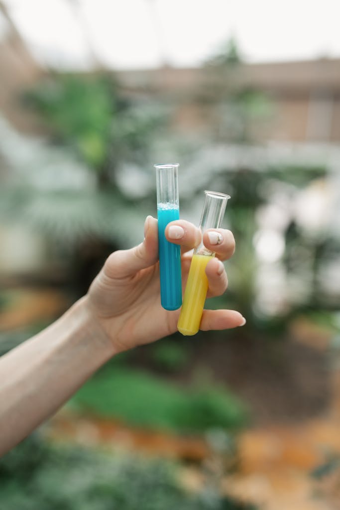 Vibrant close-up of hands holding blue and yellow test tubes in an outdoor setting.